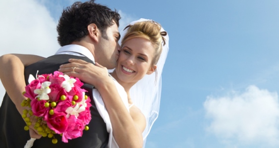 Newlywed Groom Kisses a Bride Holding a Bouquet on Her Cheek